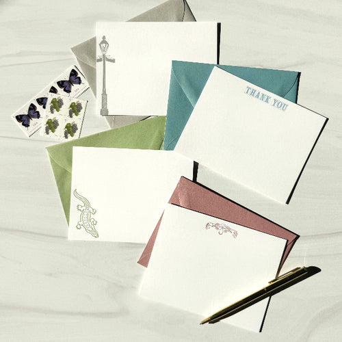 Collection of stationery items including cards and envelopes on a light wooden surface.